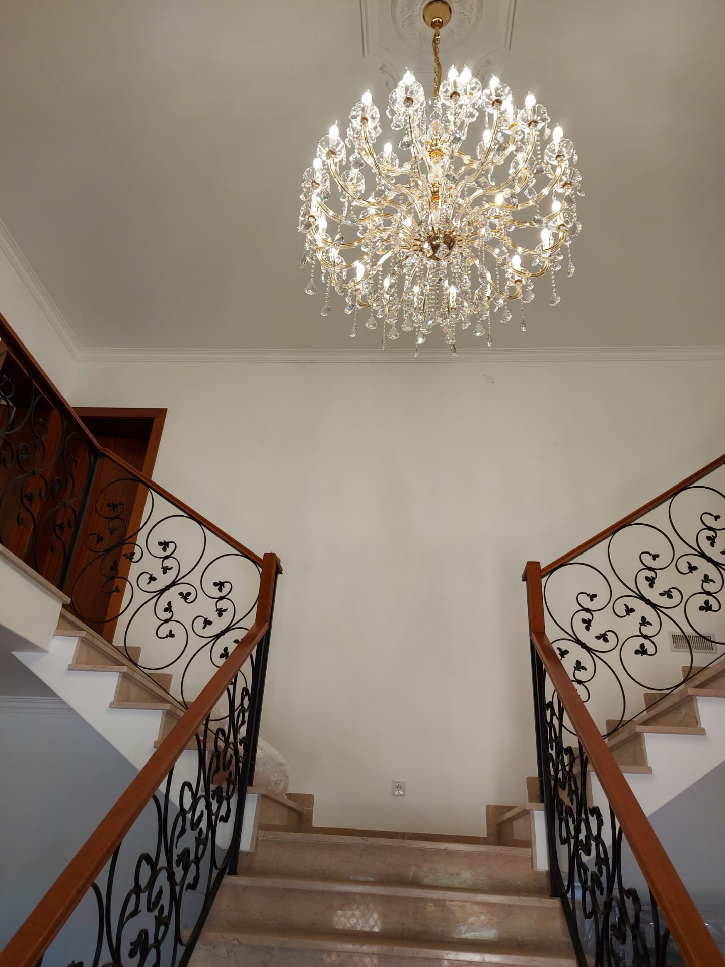 Wrought-iron staircase under crystal chandelier