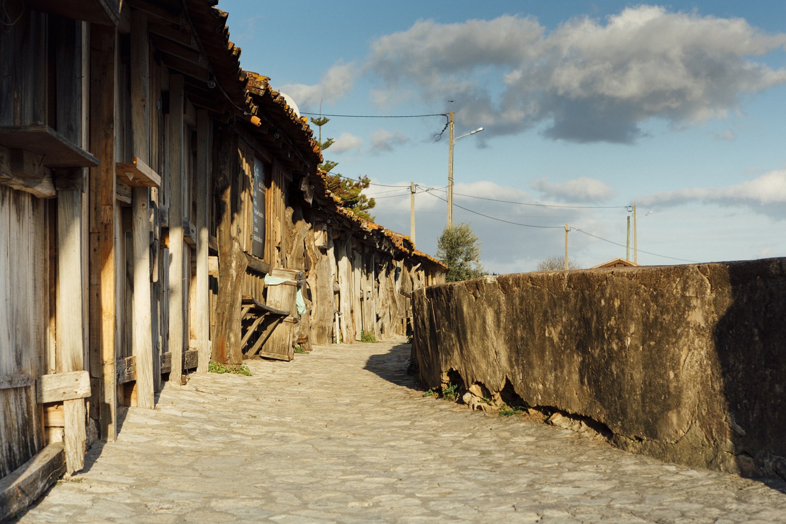 Cobblestone path between 19th-century wooden salt-storage huts in Marinhas do Sal village, beside the Salinas de Rio Maior